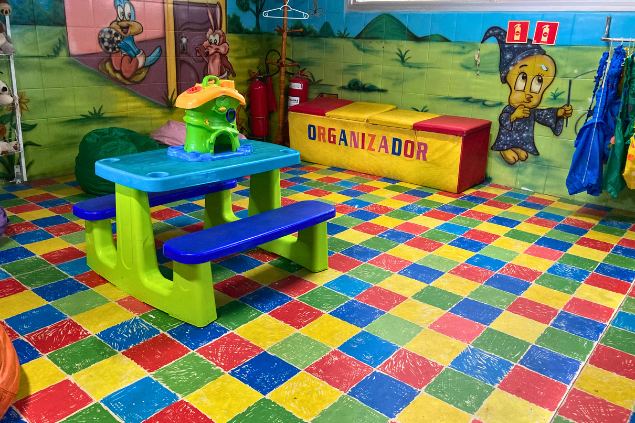 Mesas e cadeiras infantis coloridas sobre piso emborrachado
