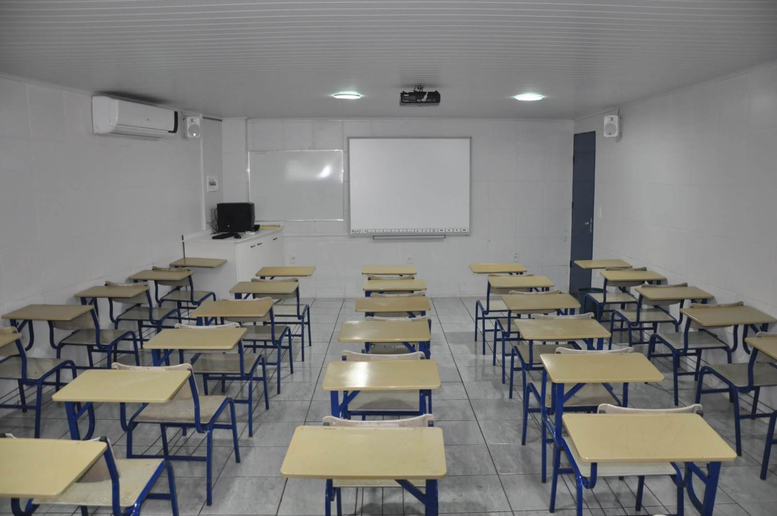 Sala de aula com carteiras, quadro branco e projetor