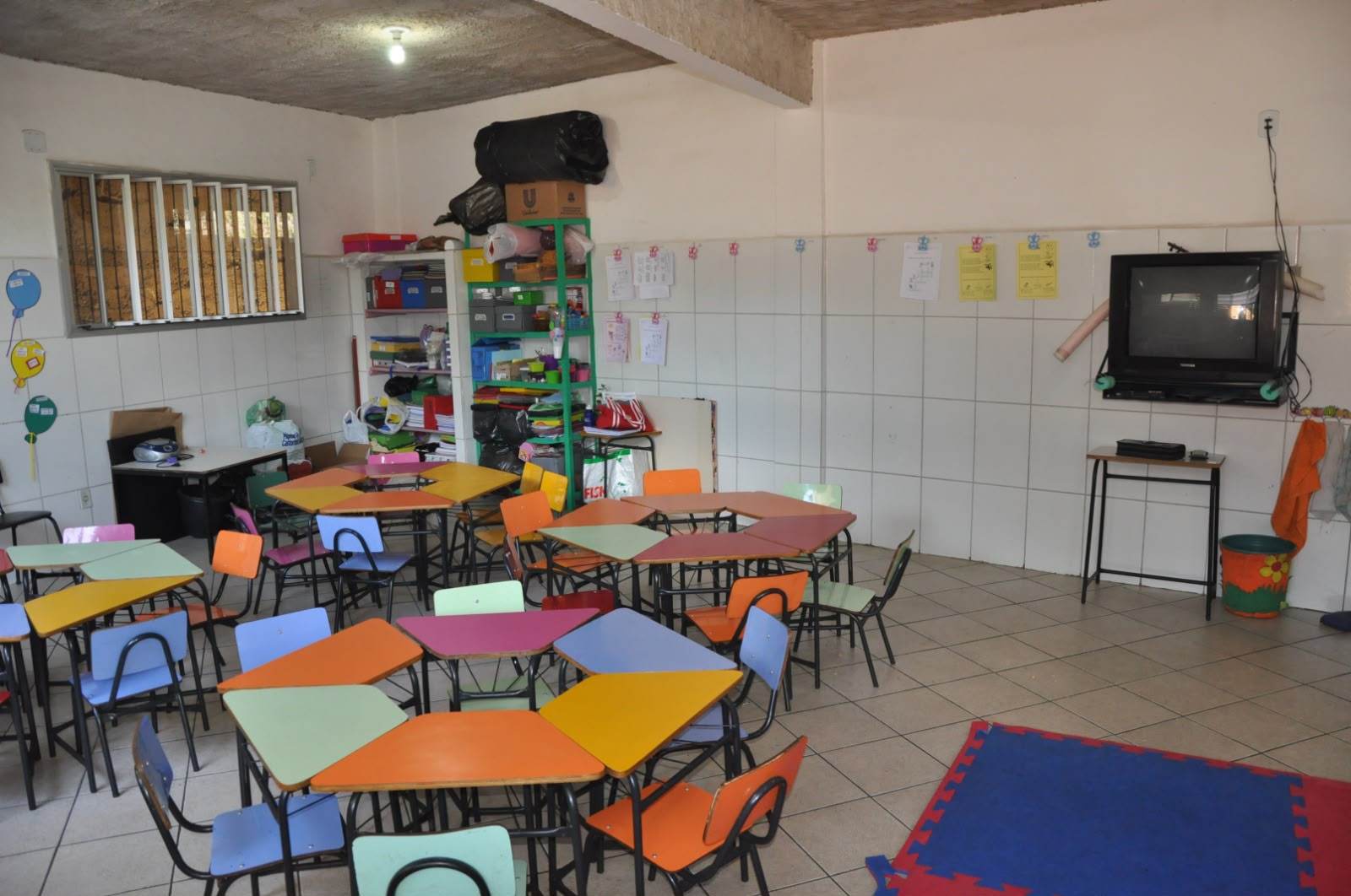Sala de aula com mesas e cadeiras coloridas