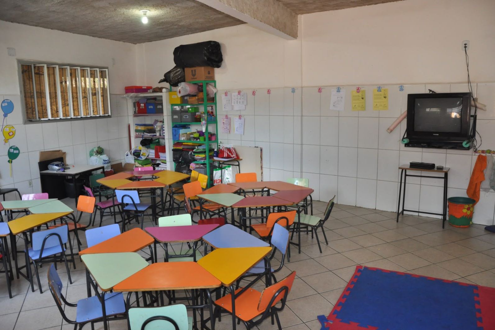 Sala de aula com mesas e cadeiras coloridas