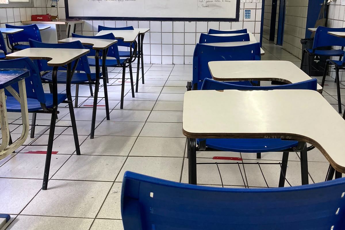 Sala de aula com quadro branco e carteiras azuis